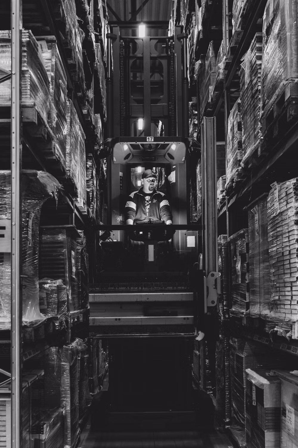 Warehouse worker operating a forklift between storage racks
